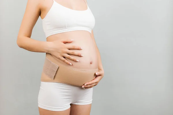 用灰色背景的怀孕腰带和影印空间 对穿着内裤的孕妇进行近距离检查 整形外科腹部支持带概念 — 图库照片