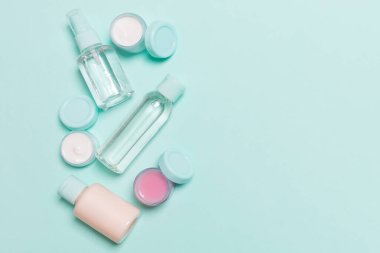 Mavi arka plandaki kozmetik ürünleri için küçük gezici şişelerin ve kavanozların üst görünümü. Tasarımınız için kopya alanı olan yüz bakımı konsepti.