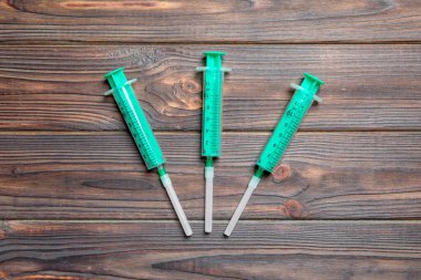 Ahşap zemin üzerindeki şırıngaların fotokopi alanı ile üst görüntüsü. Enjeksiyon konsepti için tıbbi ekipman.