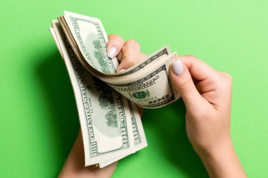 İş kadınının elleri renkli arka planda 100 dolarlık banknotları sayıyor. Maaş ve ücret kavramı. Yatırım kavramına en üst düzey bakış.