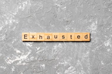 Tahta bloğa yazılmış tükenmiş bir kelime. Çimento masasında yorulmuş metin desing, konsept için.