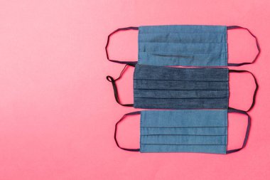 Pembe arka planda yeniden kullanılabilir ev yapımı tekstil maskelerinin üst görüntüsü. Fotokopi alanı ile solunum koruma kavramı. DIY kavramı.