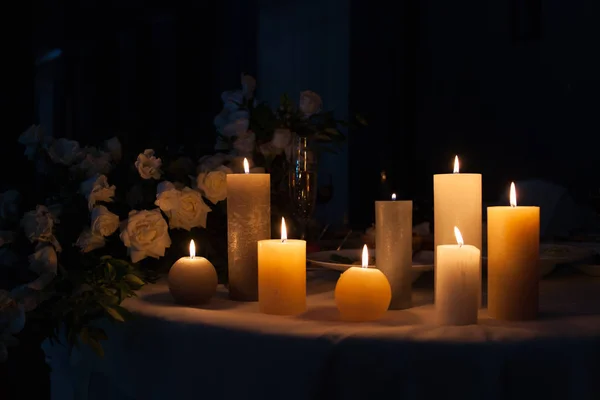 Weiße Rose und brennende Kerzen auf einem Tisch im Dunkeln, Dekoration eines festlichen Esstisches, Platz für Text. — Stockfoto