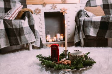 Noel ağacı dalları, yanan mumlar, koniler, kurabiyeler, oyuncaklar ile süslenmiş demir bir tepside bir fincan sıcak bitki çayı. Noel arkaplanı. Yeni yıl havası.