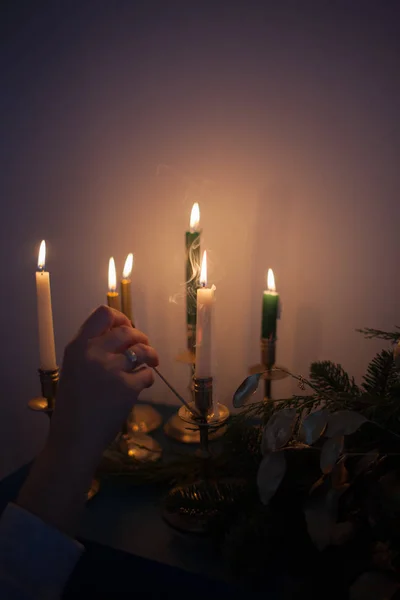 Decoração de Natal com velas em chamas e ramos de árvore de Natal. Estilo vintage tonificado imagem. Mulher acende velas — Fotografia de Stock