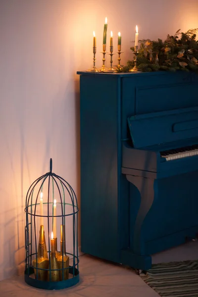 Uzun bir Noel çelengi ile süslenmiş mavi renkli eski bir piyano ve bayramı kutlamak için yanan mumlar. Şenlik dekorunun altın unsurları. Kış Tatili Konsepti. — Stok fotoğraf