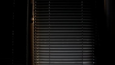 Bir adam panjurları açar ve kapatır. Panjurlar açılıp kapanıyor.