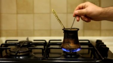 Bakır bir Türk 'te öğütülmüş sade kahve demlenir ve gaz sobasında kaynatılır. Barista evde lezzetli bir şeyler hazırlıyor..