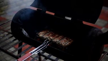 Izgarada sosis pişirmek. Açık barbeküde metal ızgarada sulu et sosisleri tüttürüyorum..