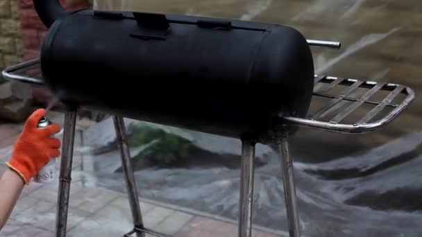 Een Man Schildert Een Metalen Oppervlak Van Een Barbecue Met — Stockvideo