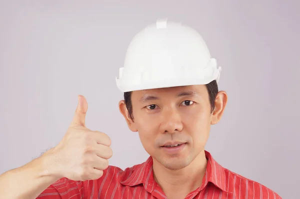 Mühendis giymek kırmızı gömlek ve beyaz şapka yapmak sinyal başparmak — Stok fotoğraf