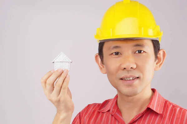 Engenheiro usar camisa vermelha e amarelo engenheiro chapéu segurando casa — Fotografia de Stock