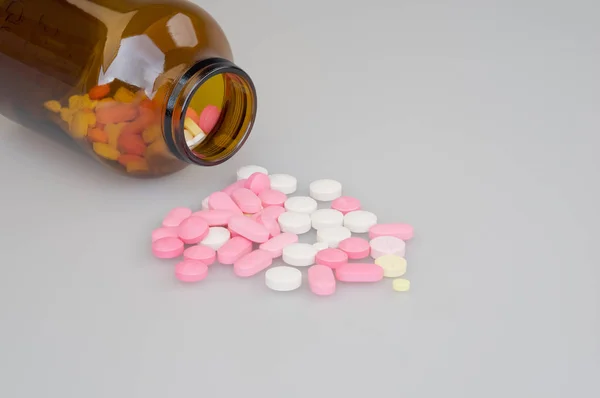 Bunte Tabletten und braune Flasche mit weißem Hintergrund — Stockfoto