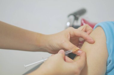 Hemşire holding şırınga şırınga tekerlekli sandalye üzerinde hasta ile aşı enjekte