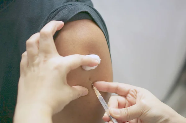 Enfermeira segurando seringa hipodérmica está injetando vacina com o homem paciente — Fotografia de Stock