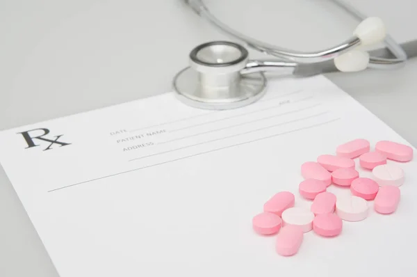 Nahaufnahme Pillen auf verschwommenem rx Rezeptformular mit Stethoskop — Stockfoto