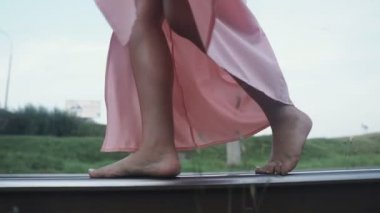 Raylarda yalın ayak yürüyen bir kızın yakın çekimi..