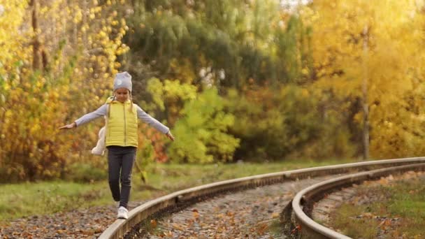 Une petite fille marche sur les rails et admire la nature . — Video