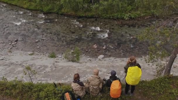 Ovanifrån av vandrare med stora ryggsäckar grupp vilar på floden bergsbanken — Stockvideo