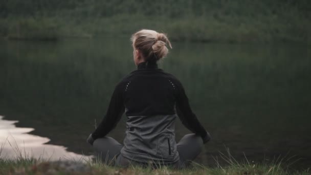 Blond kvinna som utövar yoga vid sjön. Harmoni och meditation. — Stockvideo