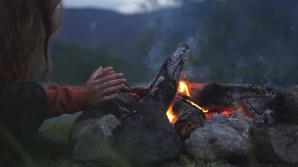 Mladá dívka se snaží udržet teplo u ohně — Stock video