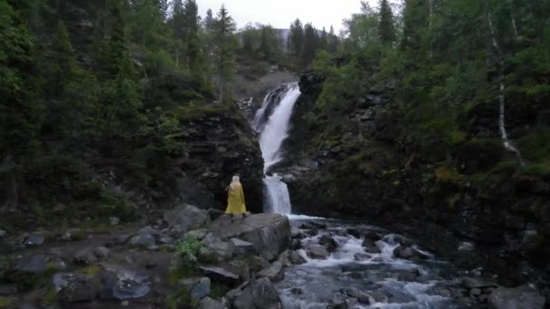 Vue aérienne depuis le dos d'une voyageuse aux longs cheveux blonds admire la belle cascade — Video