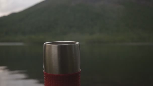 Steaming coffee or tea in a thermo cup on Mountain view in the background. — Stock Video