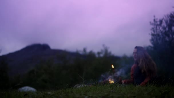 Vrouwelijke reiziger zittend op gras nabij vuur in Hibiny. — Stockvideo