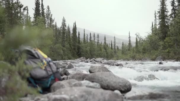 Туристический рюкзак на фоне горной реки — стоковое видео