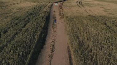 Küçük çocuk gün batımında yeşil çayırda uçurtmayla oynuyor.