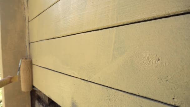 Cerca, mano en guante protector pintura casa de madera con un rodillo de pintura — Vídeos de Stock