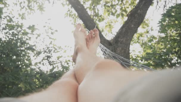 Gelukkig, jonge man ontspannen op hangmat in de tuin — Stockvideo