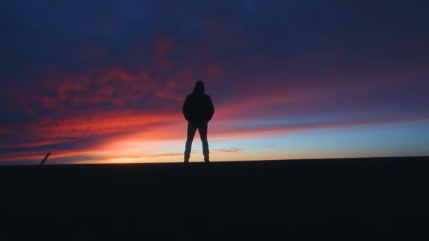 Osamělá postava muže, který stojí na pozadí západu slunce — Stock video
