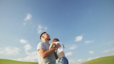 Mutlu baba, küçük oğlunu mavi gökyüzünün arka planına fırlatıyor..