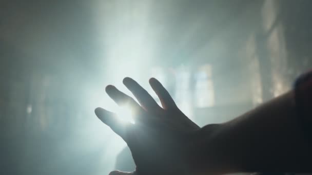 Silhouette of a Hand against a sunrays. Sunlight shining between fingers — Stock Video