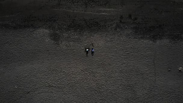 Dos personas se encuentran en la arena negra de una playa. Océano Atlántico en Islandia . — Vídeos de Stock