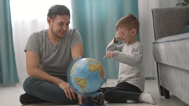 Отец и ребенок проводят время вместе. Папа и сын смотрят на Глобус — стоковое видео