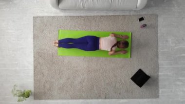 Genç bir kadın evde tahta pozisyonu alıyor. Üst görünüm