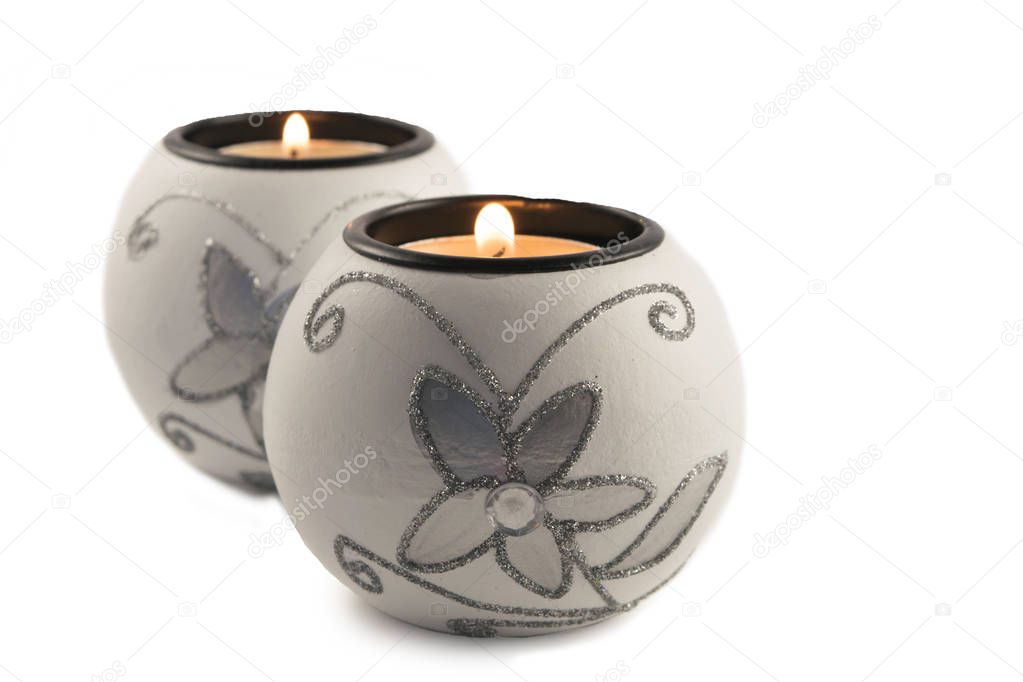 White candlestick with ball-shaped lighting candle on a white background