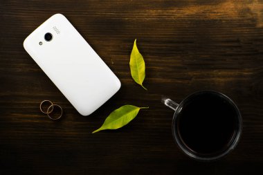 Fincan kahve, bir telefon, gözlük, eldiven, kırmızı sonbahar yaprakları