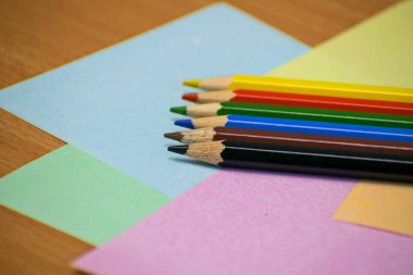 Yığın renkli kalemler yetkin ve ahşap arka plan üzerinde kapatın