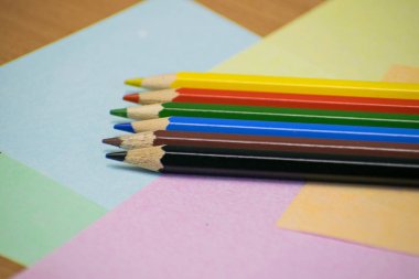 Yığın renkli kalemler yetkin ve ahşap arka plan üzerinde kapatın