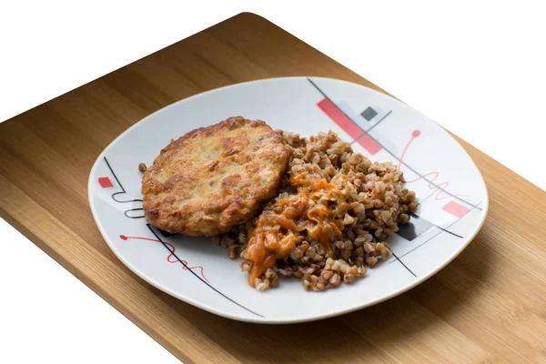 Bouillie de sarrasin avec une escalope sur une assiette blanche. Céréales de sarrasin avec schnitzel sur une planche en bois . — Photo