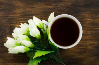 Bir fincan çay ve beyaz laleler ahşap arka plan üzerinde. Bir buket Sarı laleler ve bir fincan kahve.