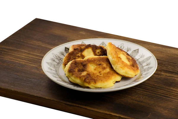 木の板に白いプレートに Syrniki。チーズのパンケーキ。朝食. — ストック写真