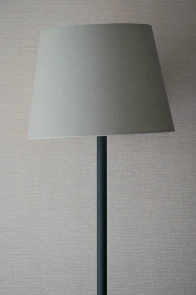 Elegant beige floor lamp. Beige floor lamp on the wall background