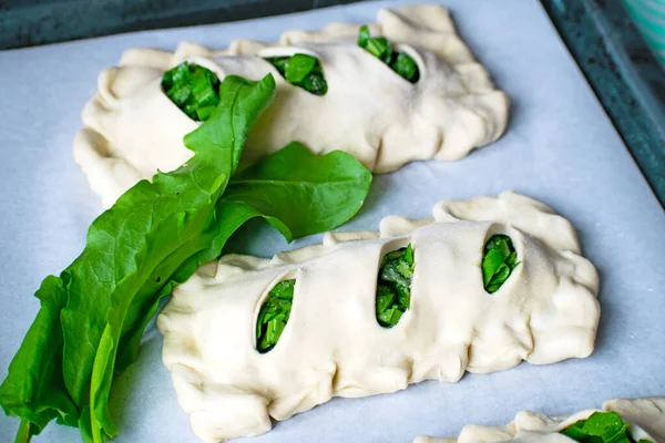 Buns of puff pastry with sorrel close-up. Homemade cakes with greens during cooking. — Stock Photo, Image