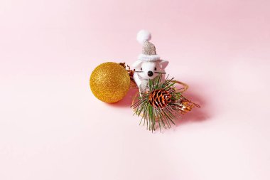 Elinde noel topu olan şirin küçük fare pembe bir arka planda oturuyor. Yılbaşı ve Noel hediyesi.