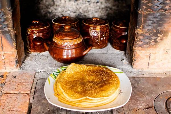 Panqueques rosados cocinados en una estufa rusa. Maslenitsa . — Foto de Stock