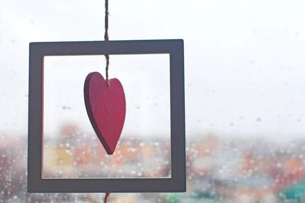 Rött hjärta på ett rep på ett fönster täckt med regndroppar. — Stockfoto